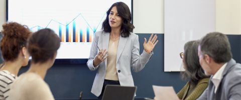 A woman gives a presentation in front of a screen 