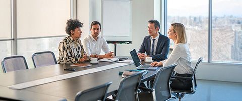 Four businesspeople have a meeting at a conference table. 