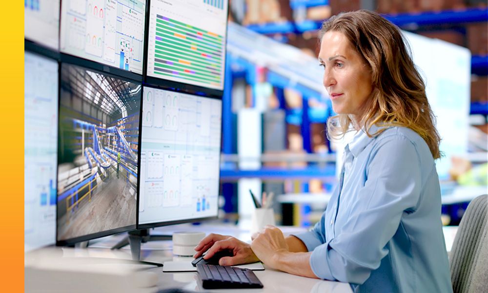 Businessperson viewing data dashboards and equipment monitoring screens at a workstation.