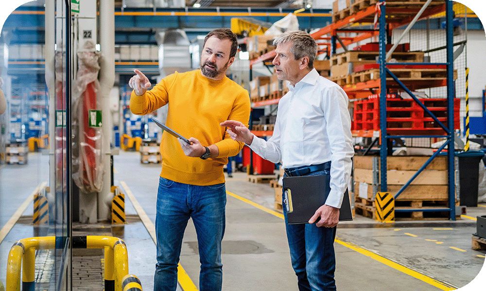 Two people reviewing information on a tablet in a warehouse. 