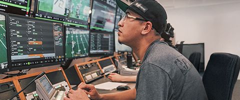 Technician monitoring multiple screens during a live sports broadcast