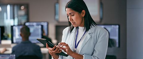 Technical analyst with computer tablet in hand reviewing problem report in operations center. 