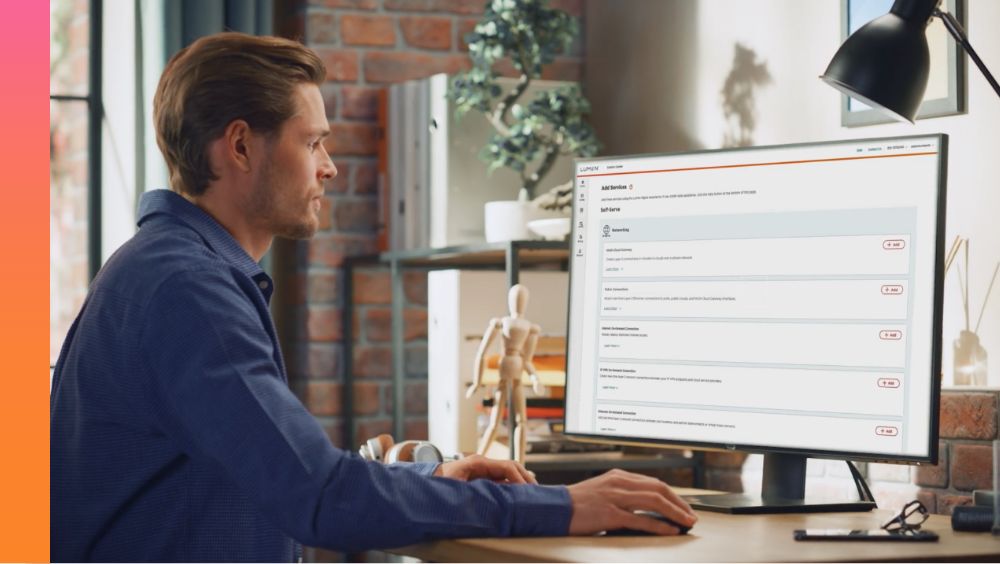 Person in a blue button-down sits at a desk and works on a monitor. 