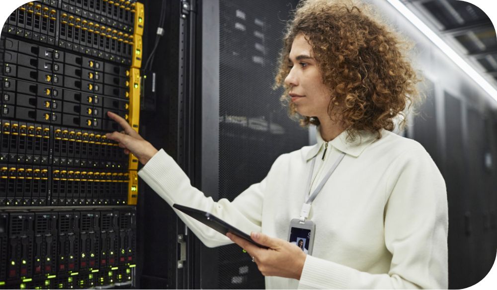 An individual holding a tablet examines data servers. 