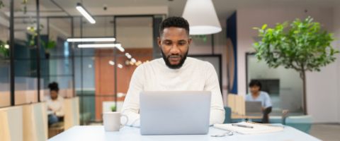 An individual sits at a desk and types on a laptop.