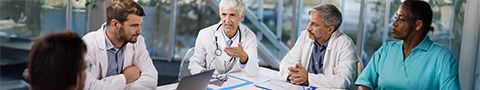 A group of medical professionals sit at a table.