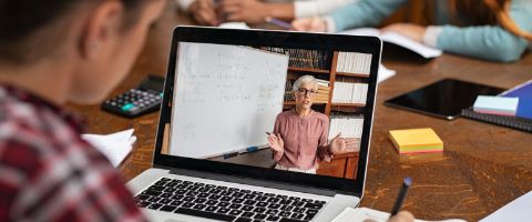 A person watches a recording of a professor on a laptop. 