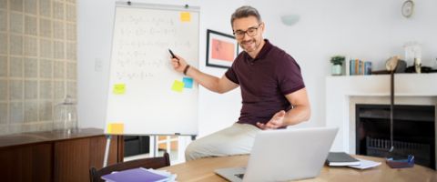 A teacher explains information written on a whiteboard to a virtual class. 