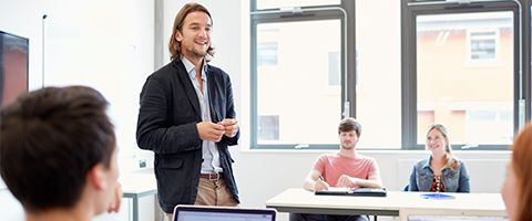 Teacher stands at front of classroom interacting with students
