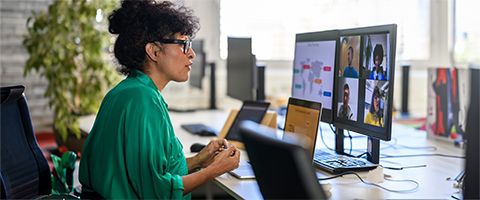 A person seated at a desk working on a computer with multiple monitors