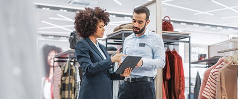 Two professionals look at a tablet together in a retail setting.