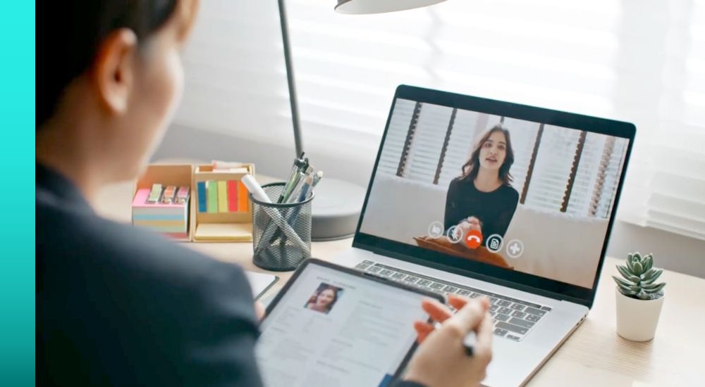 Close up of the back of a person while they're on a video chat with a woman in a black shirt