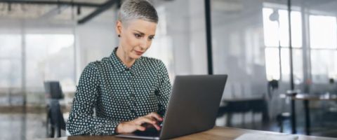 Person working on a laptop at a desk in a modern office.