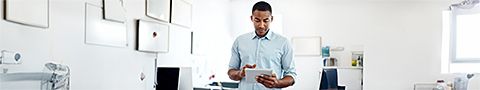 Businessperson in a light blue button-up shirt with glasses and a beard holds a tablet in front of servers