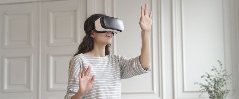 A person standing in a white room with a virtual reality headset on.