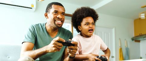 Two people sitting together holding gaming controllers.