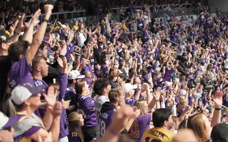 A Minnesota Vikings fan cheers for the team inside a packed stadium. 