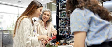 A professor explains parts of a server to two students. 