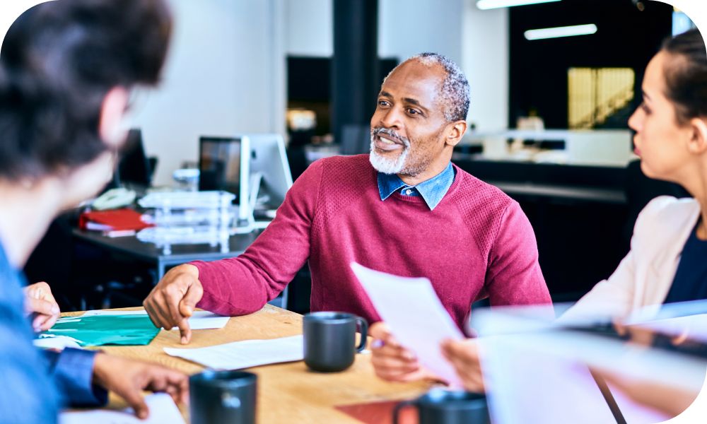 Four people having a discussion while sitting at a table inside an office