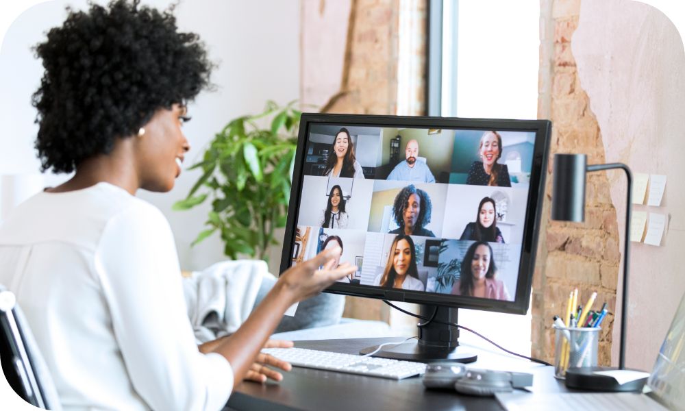 Security ops specialist conducting an online virtual meeting looking at screen with nine colleagues on the computer monitor. 