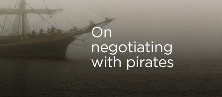 A large sailing ship is partially visible in a foggy harbor, with calm water in the foreground. The vessel appears old-fashioned, with tall masts and rigging fading into the mist. White overlay text reads "On negotiating with pirates" across the right side of the image. The overall atmosphere is mysterious and cinematic, evoking themes of conflict, diplomacy, and adventure at sea.