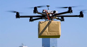Drohne liefert ein Paket mit Gebäuden im Hintergrund
