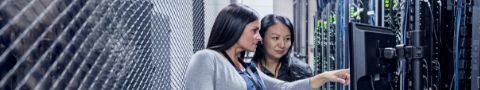 Two businesswomen having discussion while pointing at desktop