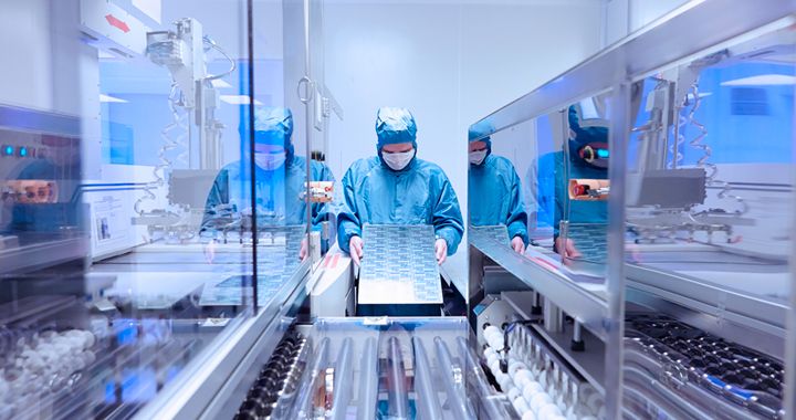 Cientista usando um uniforme limpo e segurando um equipamento em um laboratório