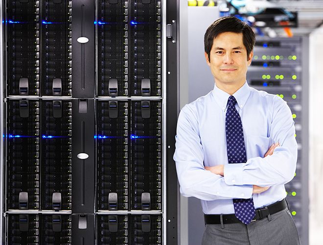Business man leaning on a server stack next to him 