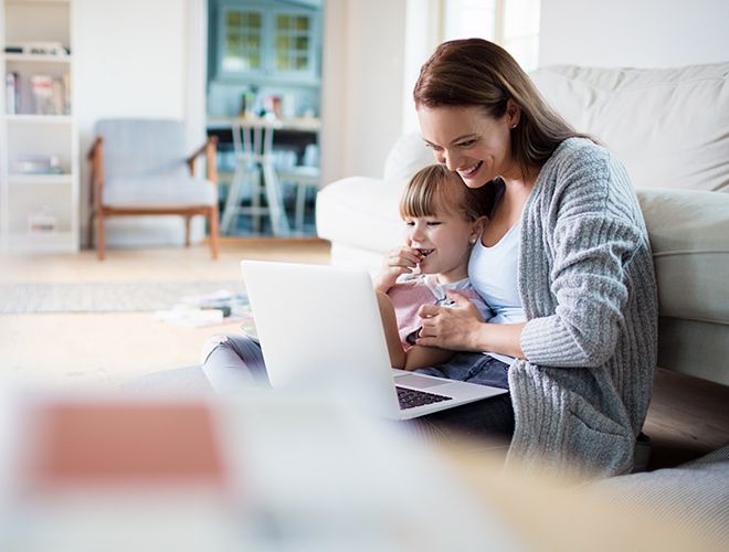 Mother and child sitting on the floor of their home looking at a laptop