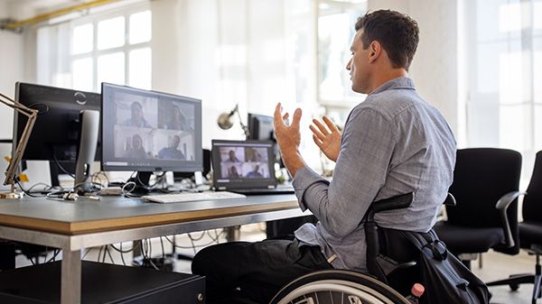 Hombre en silla de ruedas en un escritorio durante una videollamada en conferencia