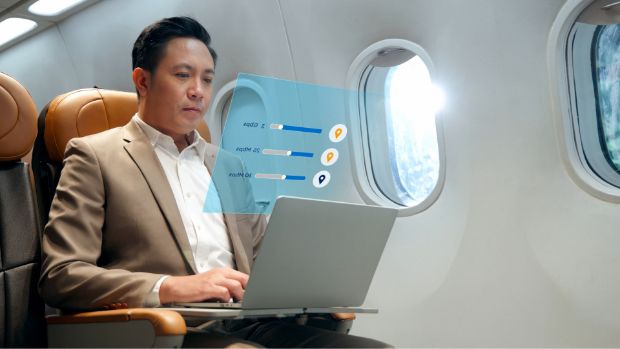 A man works on his laptop in an airplane.