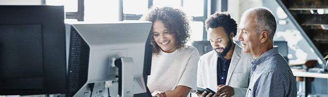 A business woman standing with two business men next to a standing desk