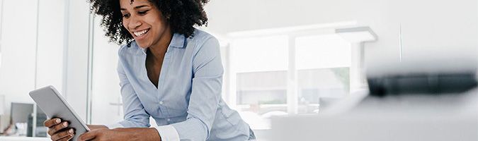 Business woman looking at a tablet device in a brightly lit office