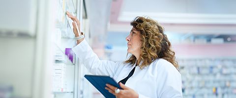 A pharmacist checks inventory on a shelf in the pharmacy