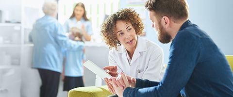 A medical professional and a patient look at information on a tablet 