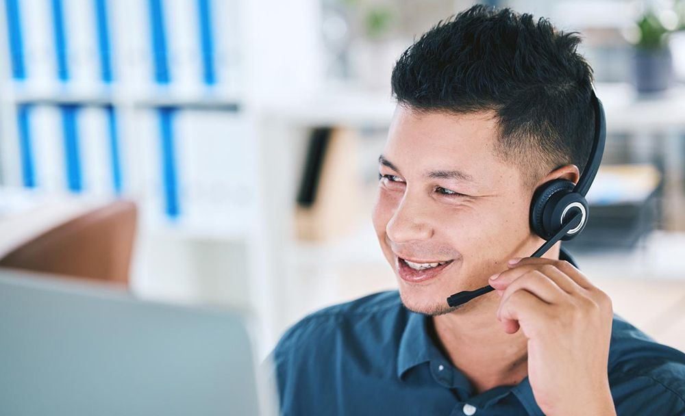 Man works from a computer screen while communicating on a headset 