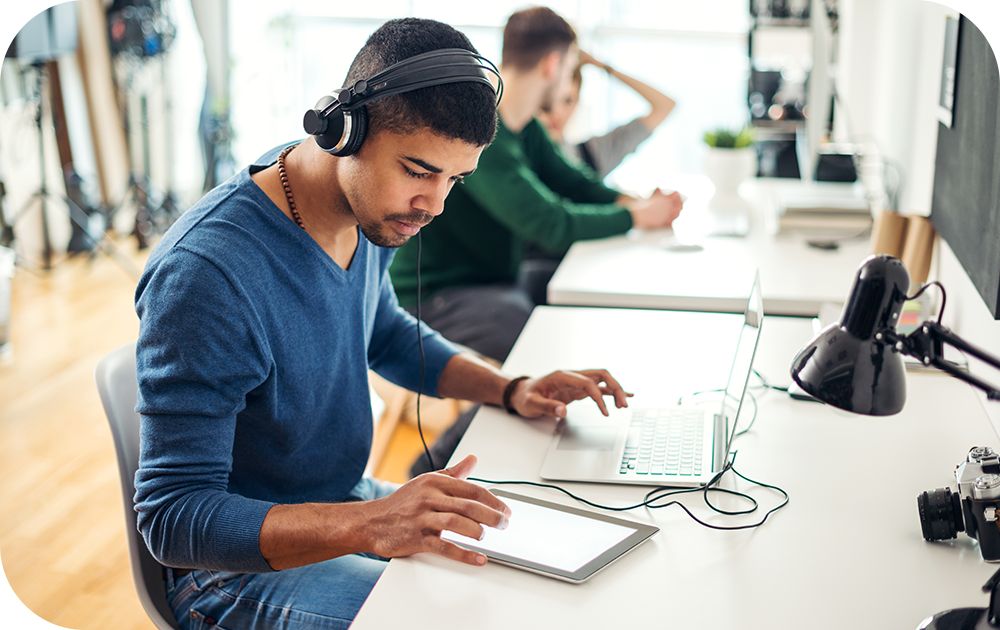 Businessperson smiles while working and utilizes a headset, monitor and keyboard 
