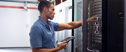 A person holding a tablet works on a server.