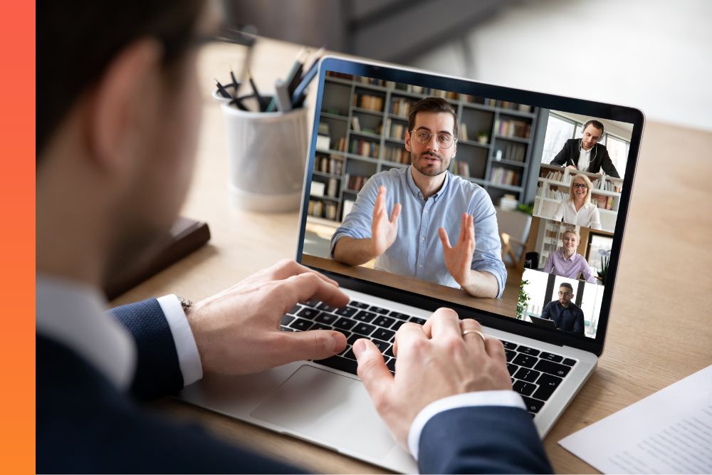 Close up of a man’s hands while sitting one a video call with five other people