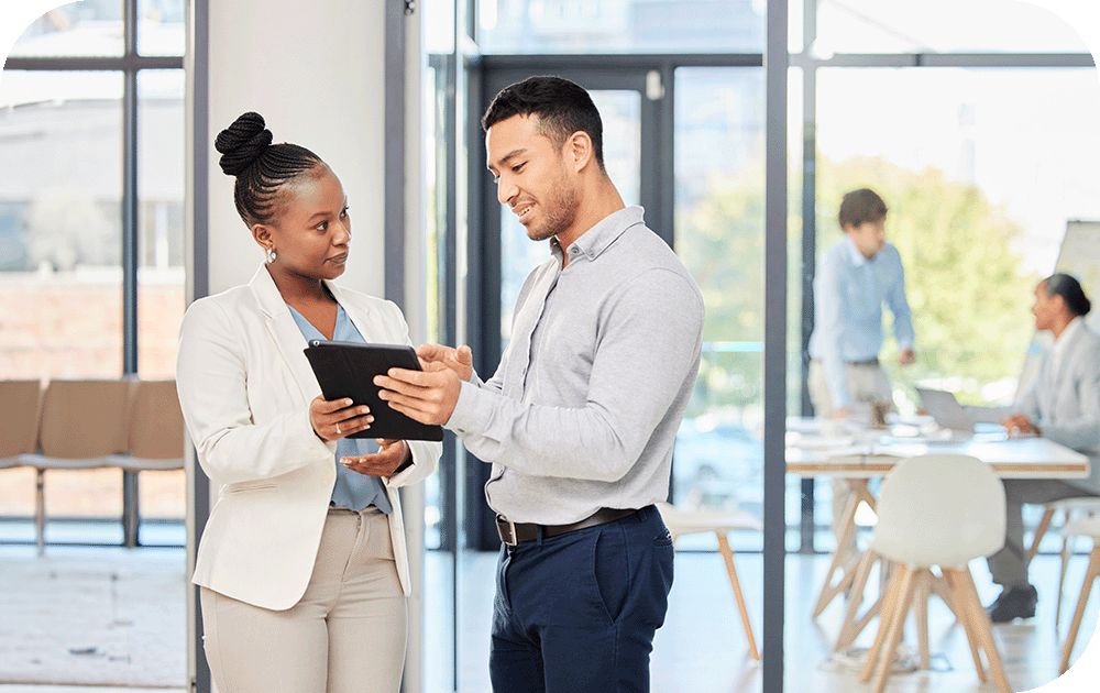 A man and a woman in the workplace work from a tablet.