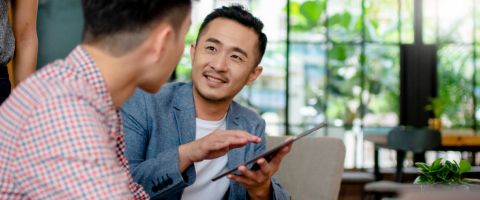 Two people having a discussion over a smart tablet.