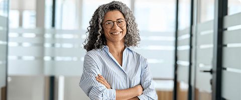 Businessperson stands posed with crossed arms and a smile.