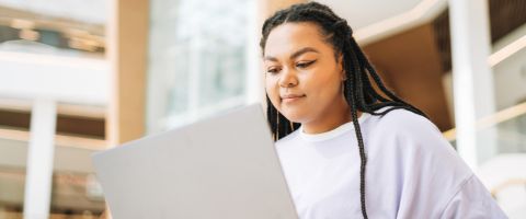 Woman in a white shirt sitting while working on a laptop in front of her