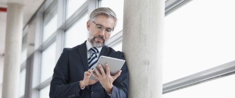 A person wearing a suit intently examines information on a tablet 