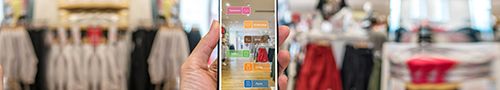 Imagem aproximada da mão de um comprador segurando um celular que mostra roupas por meio de um aplicativo de realidade aumentada