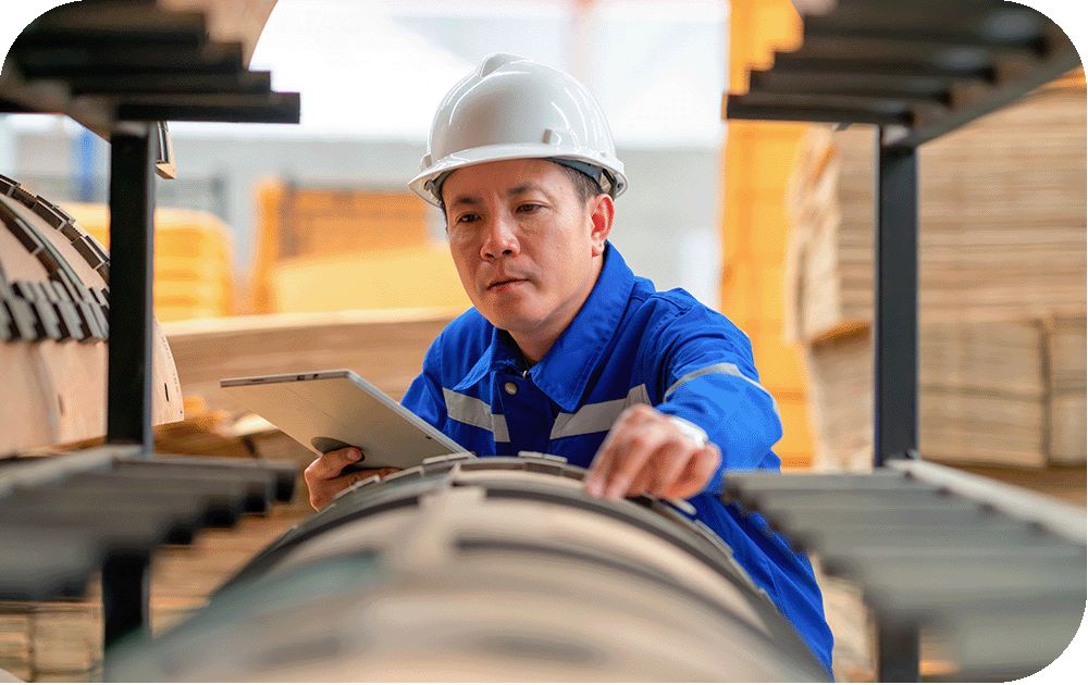 Field technician in hard hat holds a tablet and works in the field inspecting components.