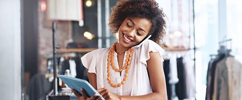 Business professional talking on cell phone while entering information into computer tablet.