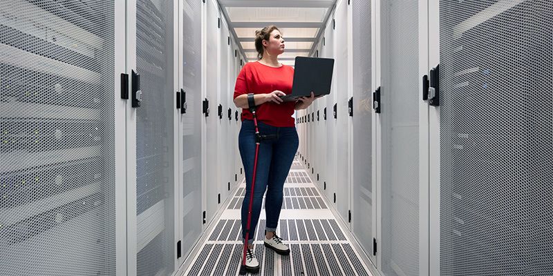 Woman walking while holding laptop in equipment room