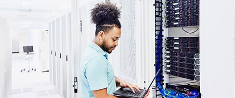 Network engineer with field test equipment checking servers in data center.